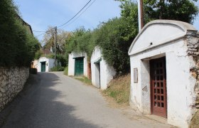 A narrow street in a wine cellar lane with white wine cellars and green doors in Herrnbaumgarten.