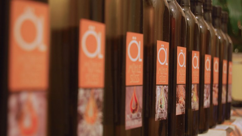 Series of &Ouml;lm&uuml;hle S&uuml;ss bottles with orange labels.