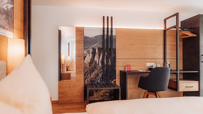 Modern hotel room with wood paneling, desk and chair.