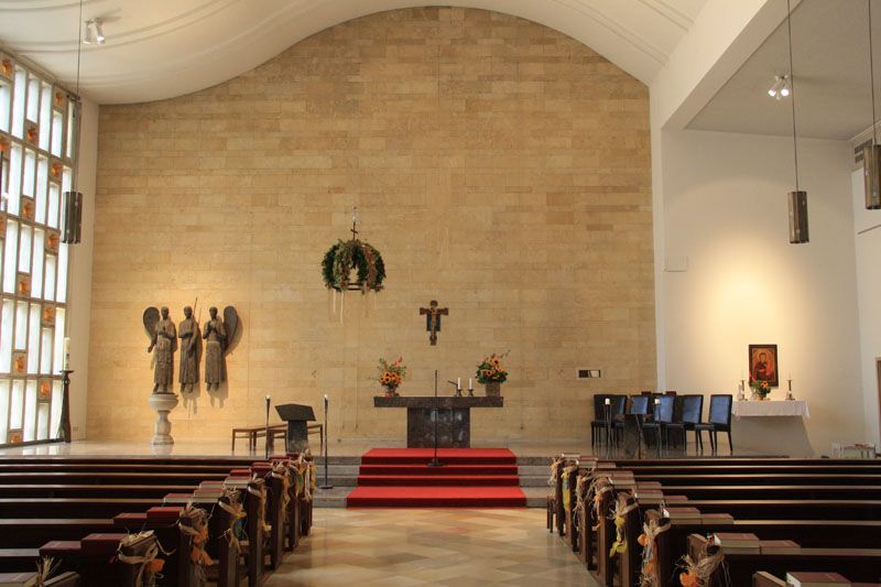 Interior view of a church with altar, pews and religious sculptures.