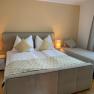 Comfortable bedroom with double bed and single bed, two bedside lamps and curtains.