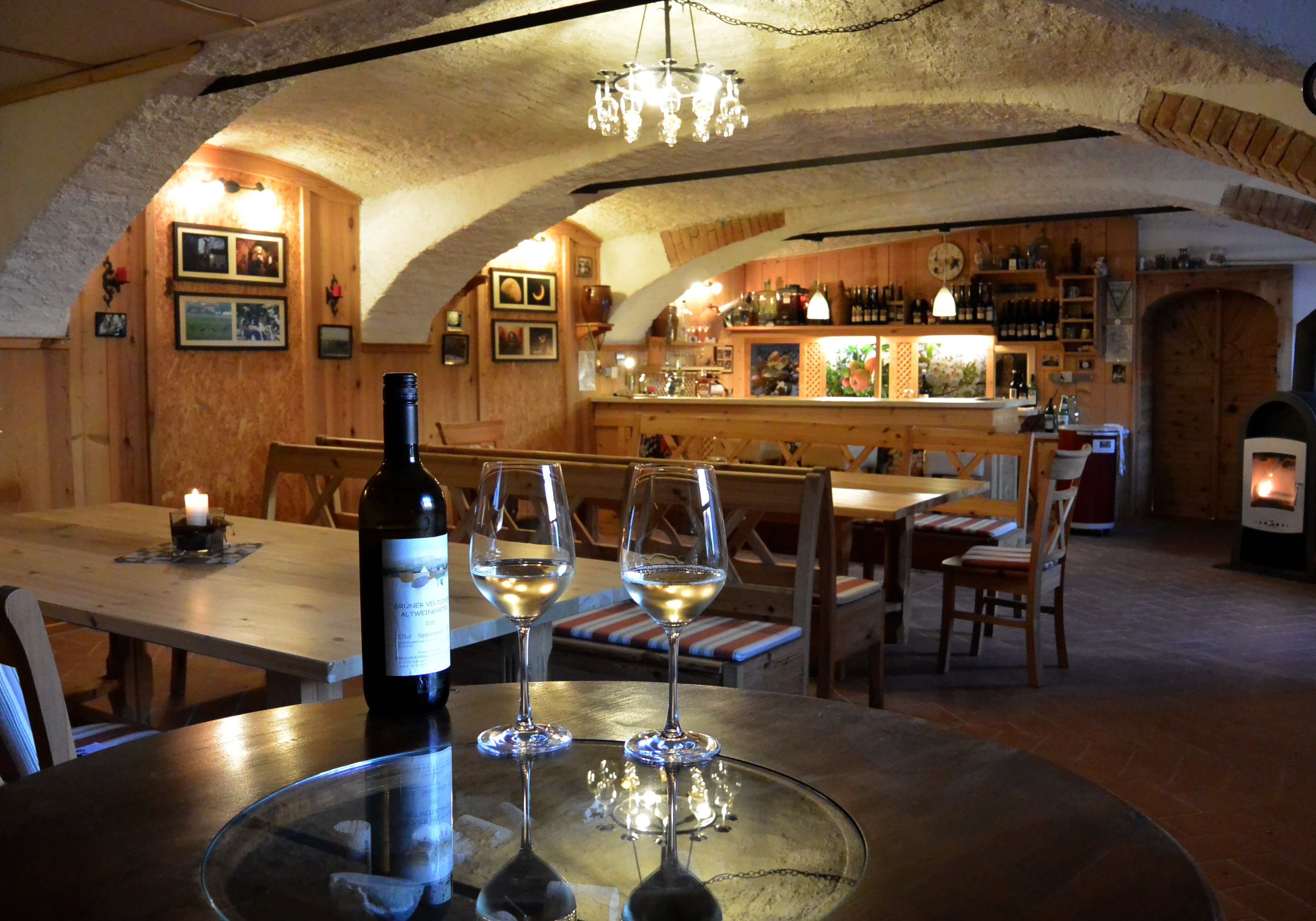 Cozy wine cellar with wooden furniture, wine bottles and glasses on a table.