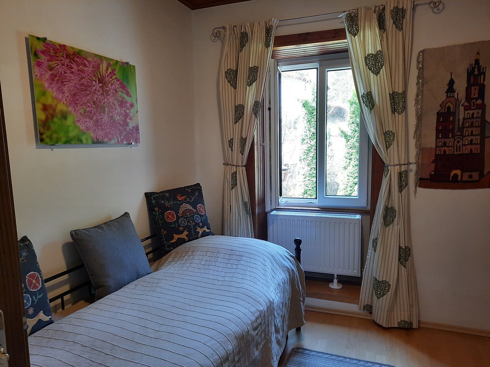 Single room with bed, window, curtains and wall decorations.