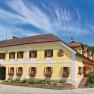 Traditional inn with yellow façade, surrounded by green landscape and blue sky.