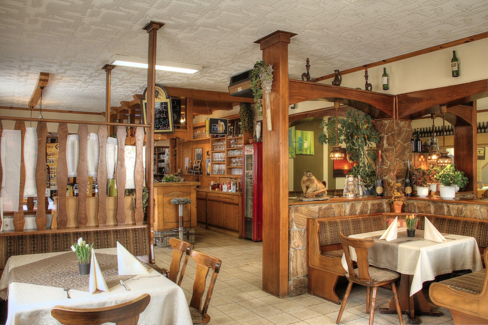 Interior view of a rustic inn with wooden furniture and decorative plants.