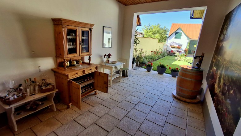 Entrance area with wooden furniture, plants and a view of a garden.