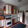 Kitchen with wooden and white cupboards, stove, sink and shelves with spices and decorations.