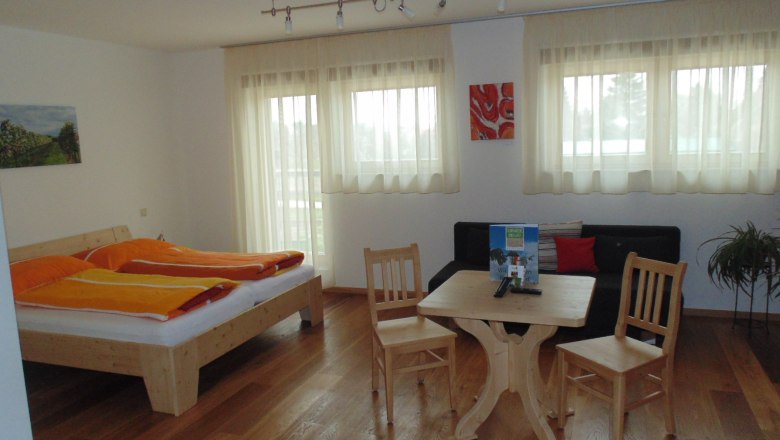 Bright room with double bed, table, chairs and sofa.