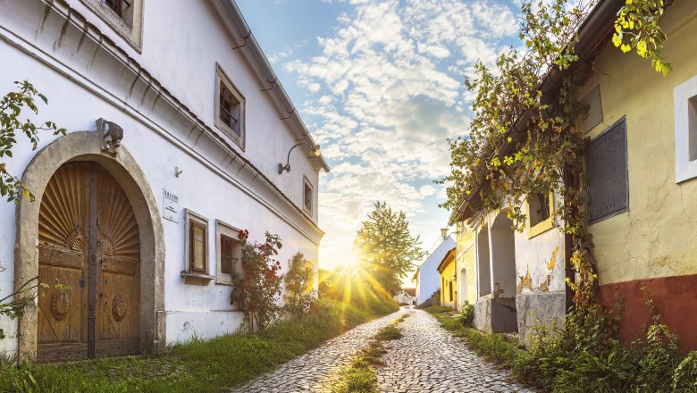 Cobblestone street in R&ouml;schitz with historic buildings and sunset.
