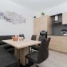 Modern kitchen with wooden furniture, dining table, corner bench and chairs.