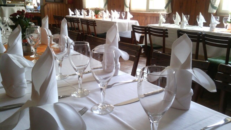 Festively laid table with white tablecloths, wine glasses and folded napkins in a restaurant.