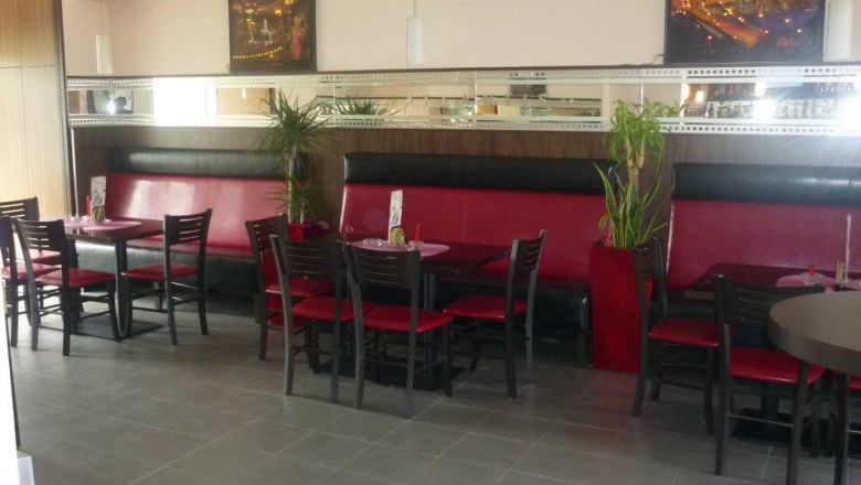 Interior view of a café with red benches and black chairs.