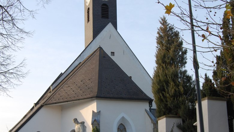 Gothic church in Kirchstetten with tower and statue in the foreground.