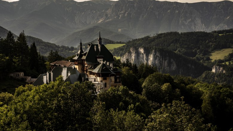 View of a historic hotel surrounded by mountain scenery