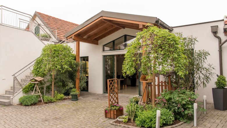 Entrance to a modern building with plants and covered entrance.