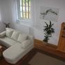 Cozy sitting area with beige sofa, wooden table, plant and shelf in a vacation apartment.