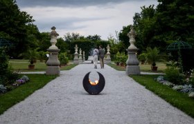 A gravel path in the historic courtyard garden of Seitenstetten Abbey with sculptures and plants, a fireplace in the foreground.