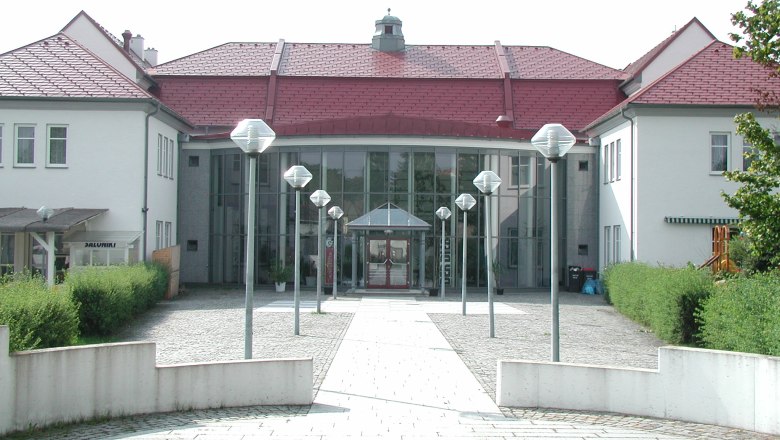 Entrance to a modern cultural center with glass façade and red roofs.