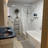 Bathroom with bathtub, double washbasin and shower with shower curtain.