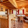 Traditional wooden kitchen with dining table, bench, chairs and red curtains.