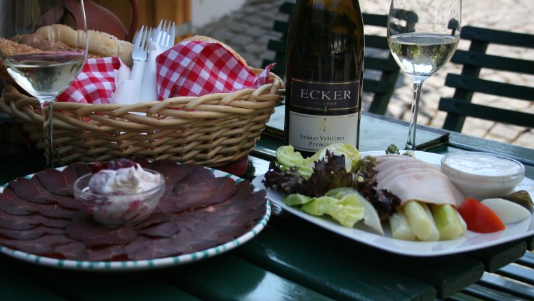 A laid table with wine, bread, cold cuts and salad.
