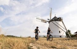 Die sanften Hügel des Weinviertels laden zu einer erfrischenden Radtour ein, während die historische Windmühle majestätisch im Hintergrund thront. Radfahrer genießen die malerische Landschaft und die frische Luft, die den Sommer in den Bergen so besonders macht.