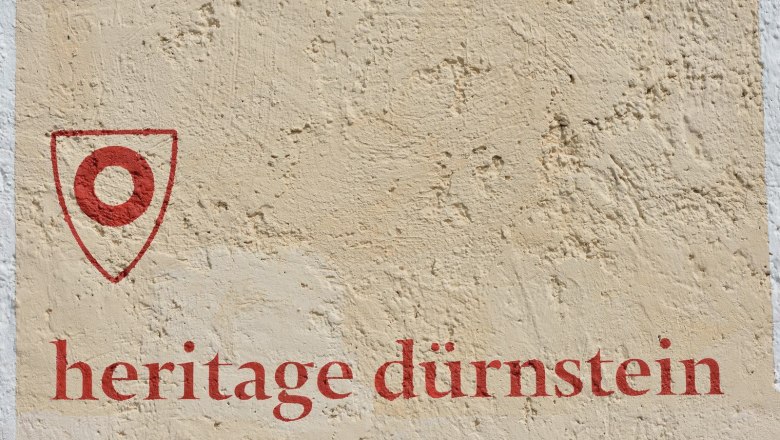 Wall with red lettering 'heritage dürnstein' and a red symbol.