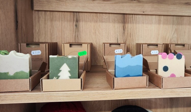 Handmade soaps in different colors and patterns on a wooden shelf.