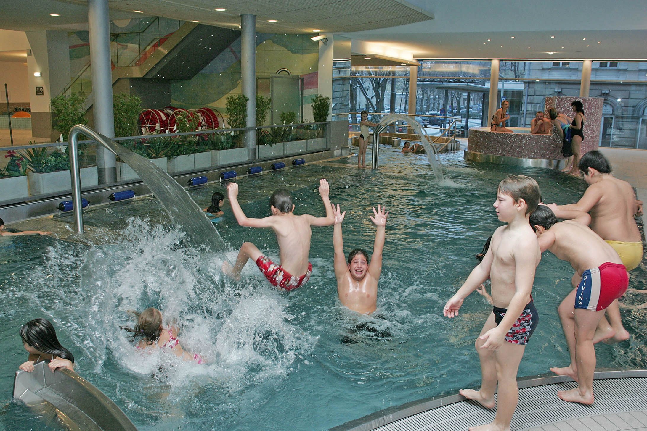 Children play and splash around in an indoor pool with water games.