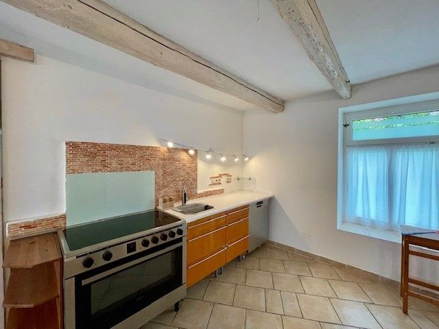 Modern kitchen with stove, wooden cupboards and tiled floor.