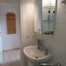 Small bathroom with washbasin, mirror and care products.