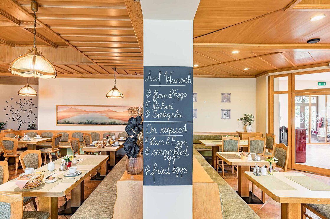 Breakfast room with wooden furniture and a board with breakfast options.