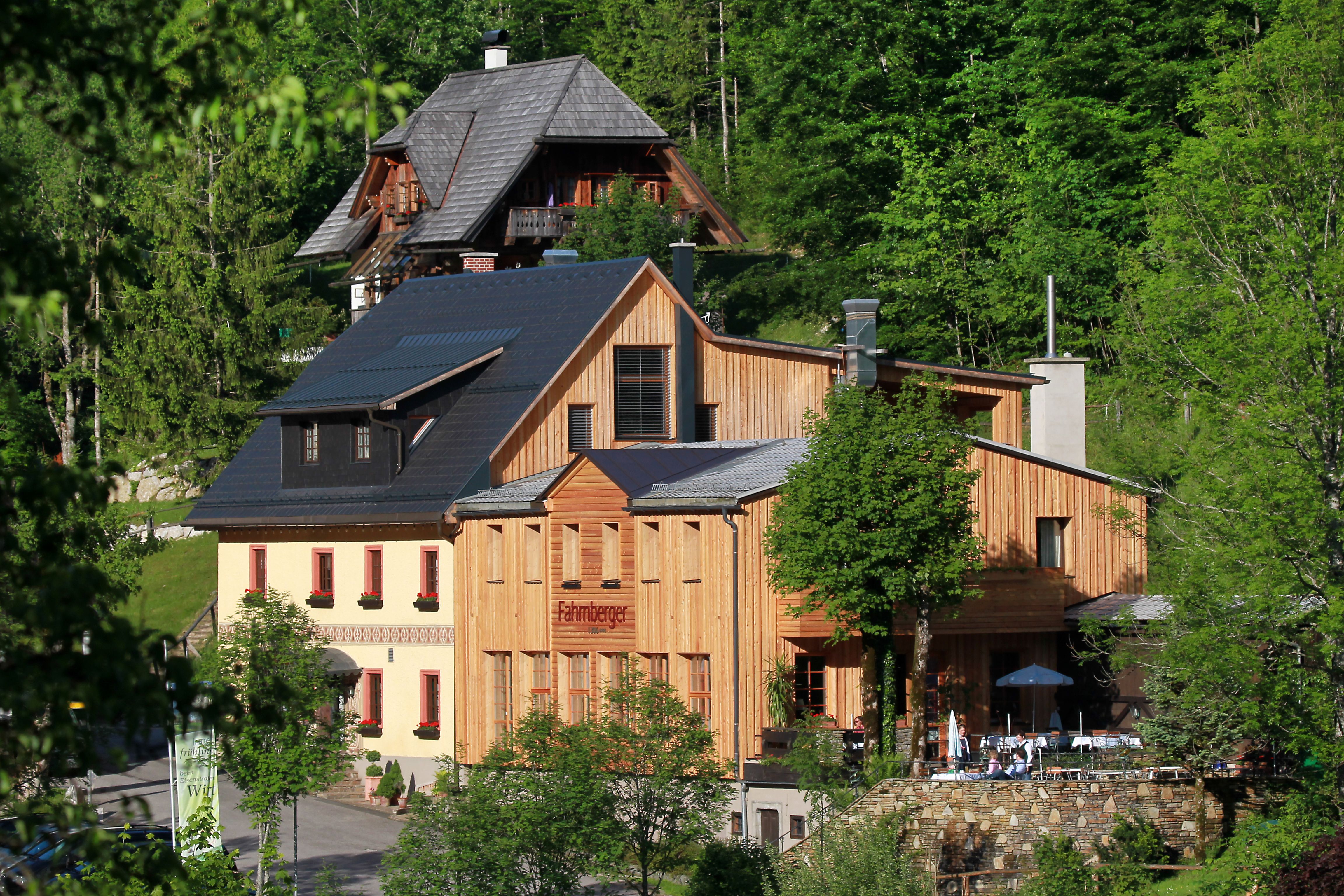A traditional building with a wooden façade in a green forest landscape.