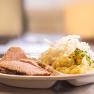 A plate of meat, sauerkraut and mashed potatoes.