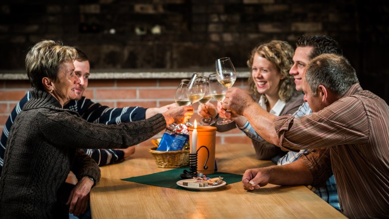 Five people clink glasses of wine at a table.