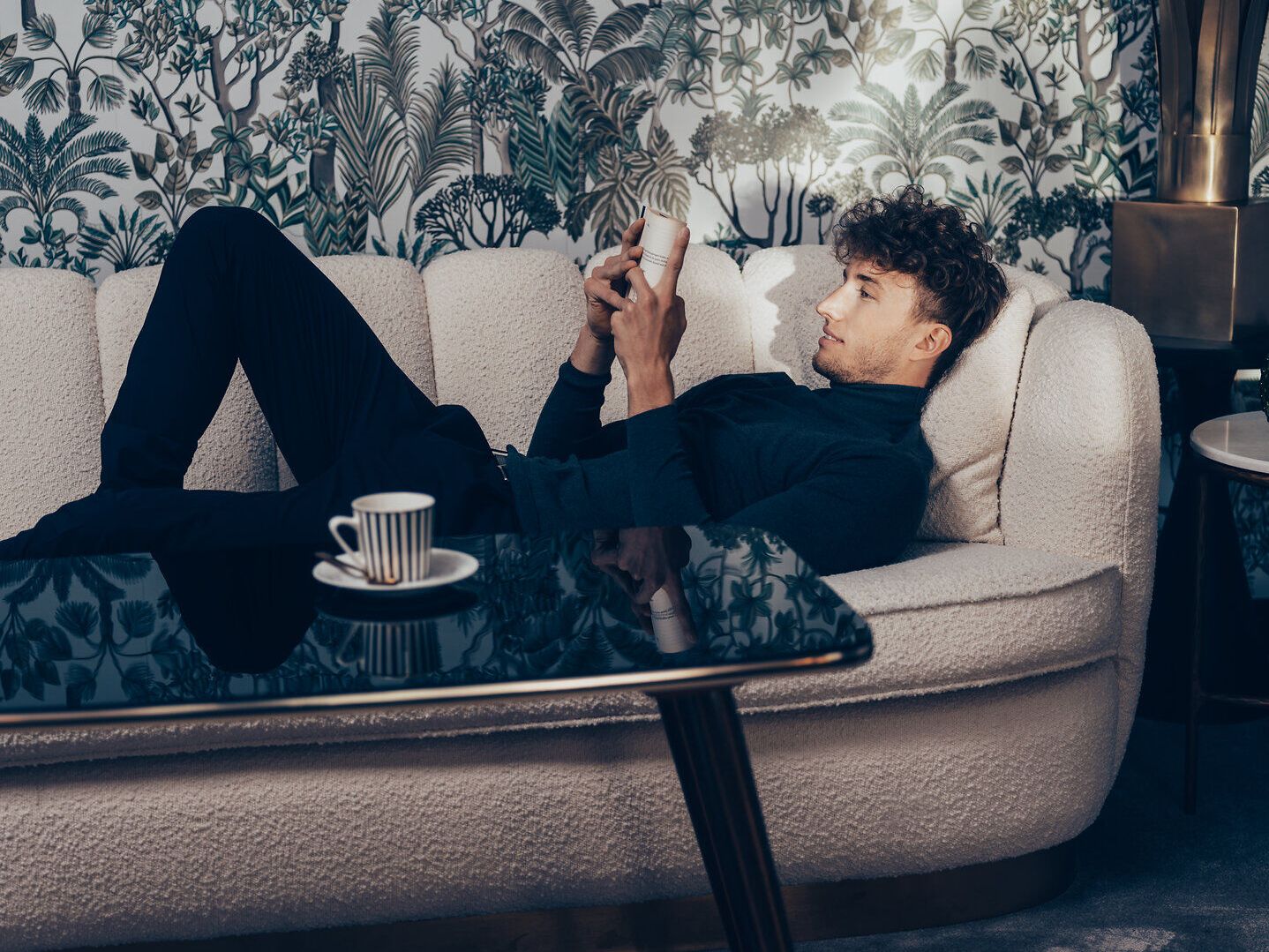 Inmitten der sanften Hügel der Wiener Alpen lädt eine gemütliche Couch zum Entspannen ein. Die üppige Pflanzenwelt im Hintergrund schafft eine harmonische Atmosphäre, während die sanften Lichtstrahlen den Raum erhellen. Hier kann man die Seele baumeln lassen und die Schönheit der Natur genießen.