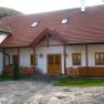 A traditional building with a red tiled roof and wooden elements, surrounded by a paved courtyard.