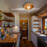 Small, cozy kitchen with wooden furniture, colorful tiles and spice racks.