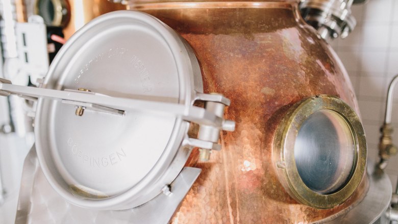 Close-up of a copper still with metal closure and viewing window.