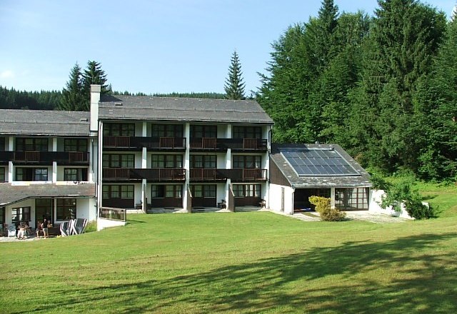 BS Ötscher Hotel in summer, © Familie Butt Hotel building with solar panels and green meadow in the foreground, surrounded by forest.