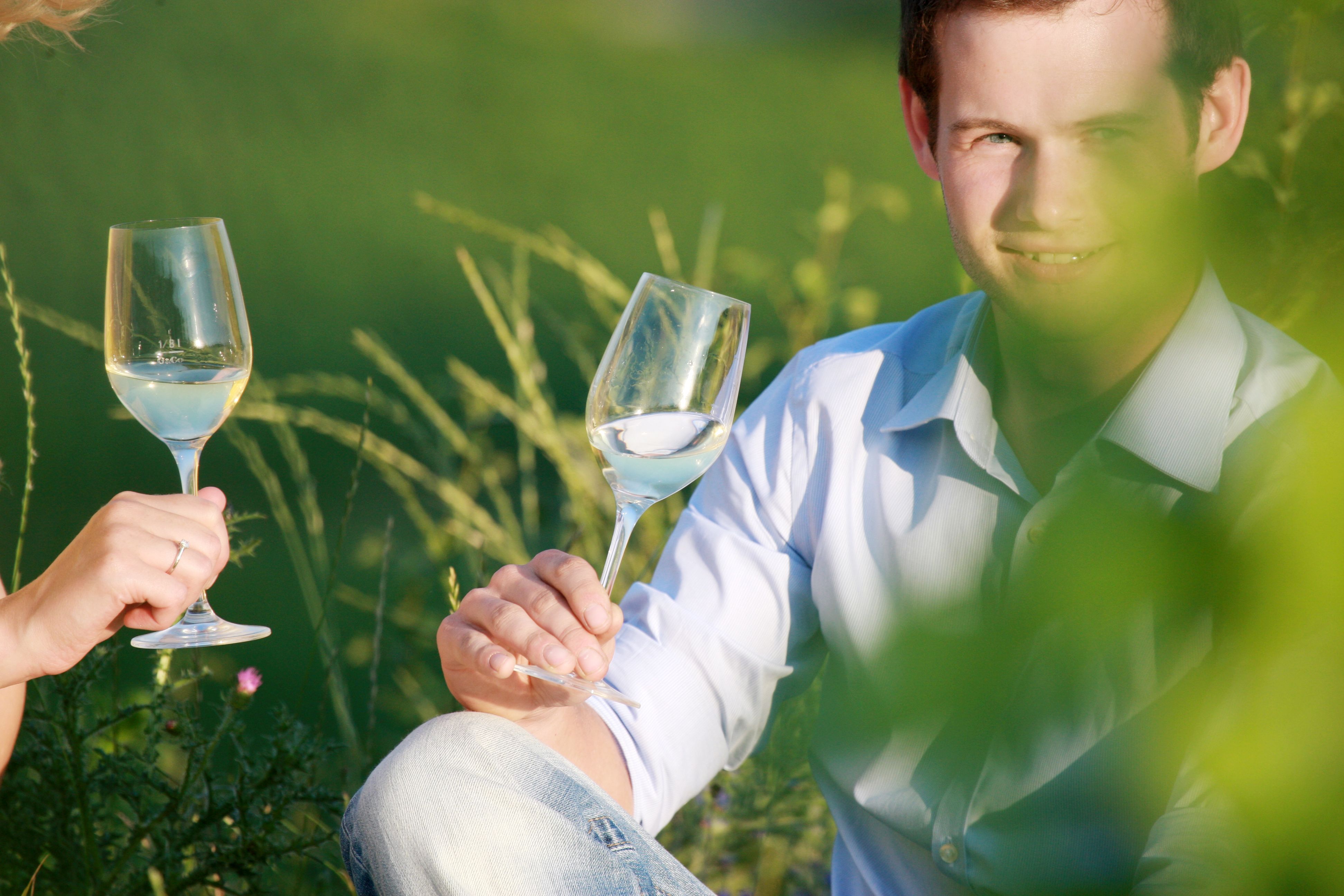 Two people clink glasses of wine outside.