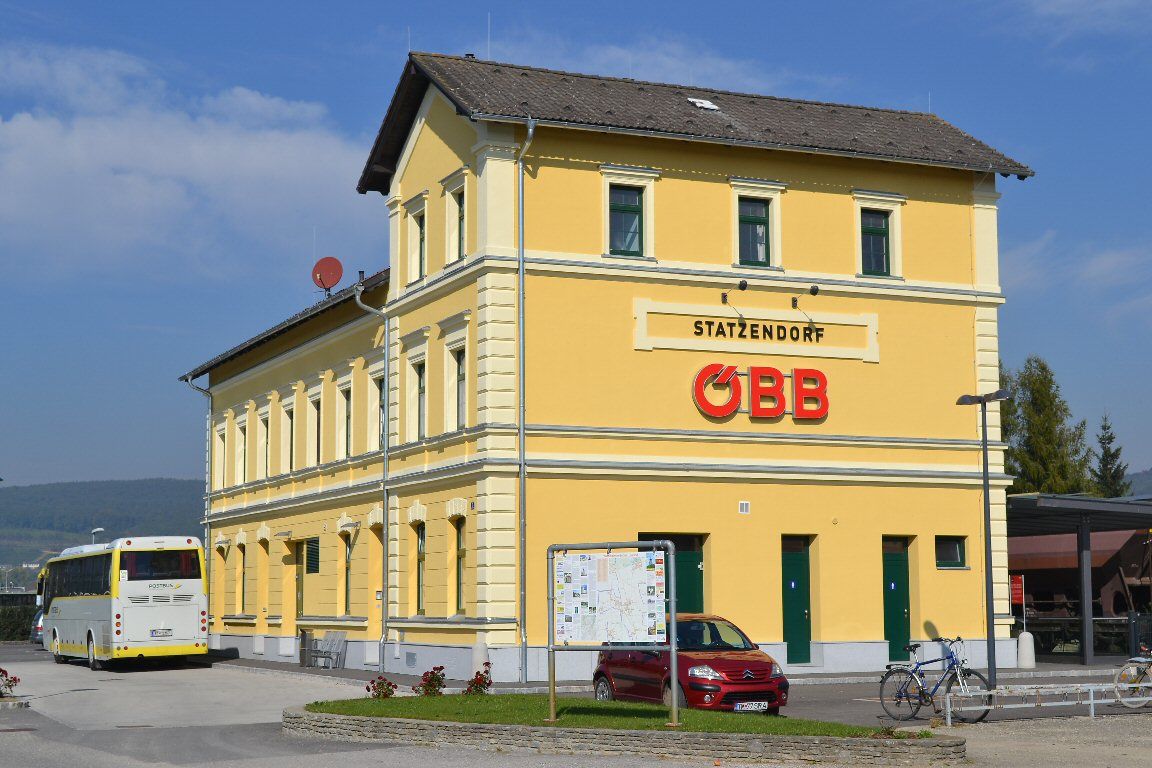 Yellow station building with ÖBB logo and bus in the foreground.