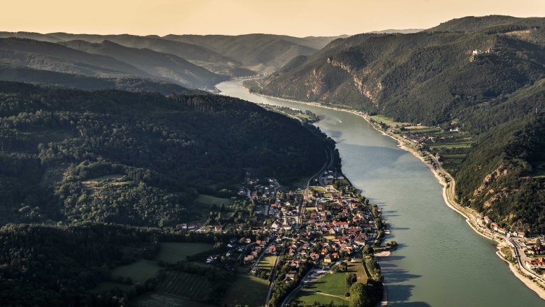 Aerial view of Aggsbach Markt an der Donau, surrounded by hills and forests.
