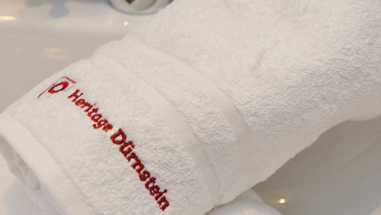 White towels with red lettering 'Heritage Dürnstein' on a washbasin with tap.