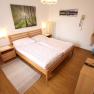 Bright bedroom with double bed, wooden furniture and pictures of nature on the wall.
