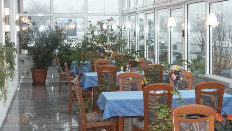 A winter garden with tables, blue tablecloths and lots of plants.