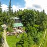 Aerial view of the Speckbacher hut surrounded by trees with terrace and guests.