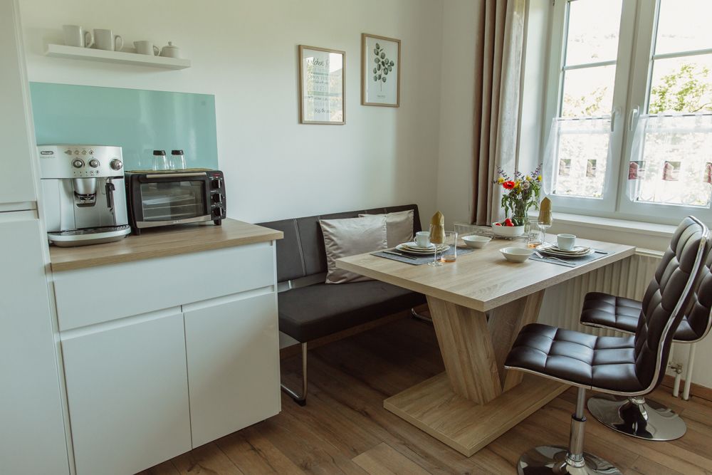 Modern kitchen with dining table, chairs and coffee machine.