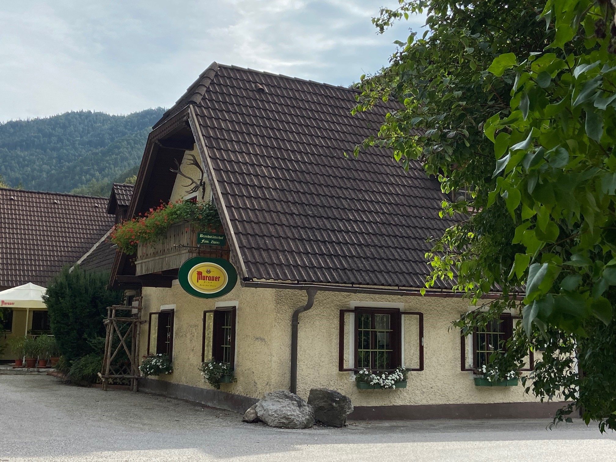 Traditional inn with flowers and Murauer sign, surrounded by trees.