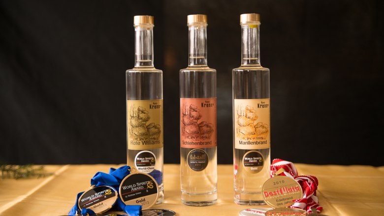 Three bottles of brandy with medals on a table.